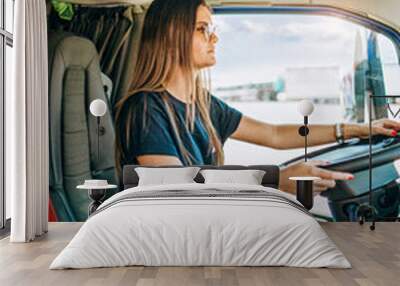 Portrait of beautiful young woman professional truck driver sitting and driving big truck. Inside of vehicle. People and transportation concept. Wall mural