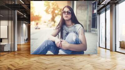 Urban vintage portrait of beautiful and attractive girl with sunglasses. Warm summer colors and haze. Strong back light. Wall mural