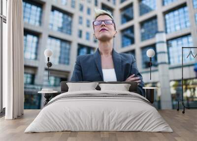 Young serious business woman standing in front of big modern building. Wall mural