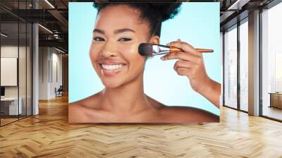 Black woman, foundation and brush in studio for beauty with skin test, smile and cosmetics by blue background. Happy african model, girl and makeup for aesthetic, glow and skincare with concealer Wall mural