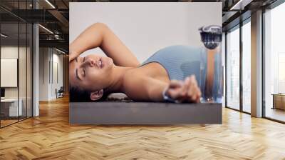 Gym floor, fatigue and woman tired after intense workout, cardio training or yoga fitness exercise. Medical dehydration problem, emergency accident injury and sports athlete faint in pilates studio Wall mural