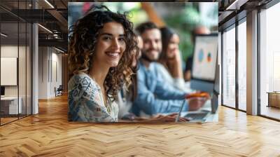 Portrait of a smiling young woman with curly hair in a casual outfit in an office setting Wall mural