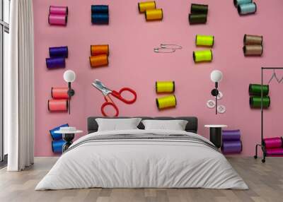 top view creative still life flat lay with reels of multicolored threads and scissors pattern on a pink background Wall mural