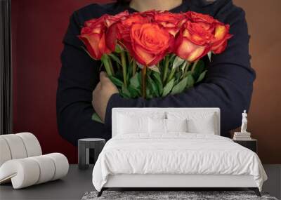 young woman in a black jacket embraces a bouquet of large roses Wall mural