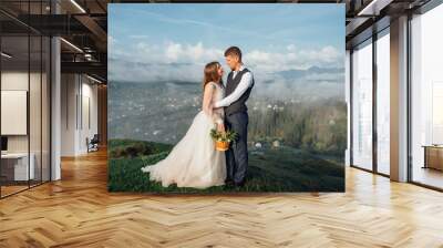 Beautiful wedding couple posing upon hills on fog Wall mural