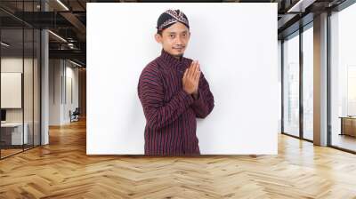 asian man with javanese traditional cloth lurik welcoming guests gretting isolated on white background Wall mural