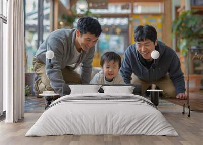 A happy baby crawls on a colorful rug, while two joyful adults kneel beside, supporting and encouraging the little one. The bright and inviting room adds to the cheerful atmosphere Wall mural