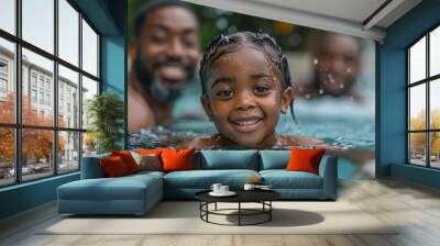 A happy child swims in a clear blue pool, enjoying time with family members who are smiling in the background. The scene captures a fun, relaxed atmosphere during summer Wall mural