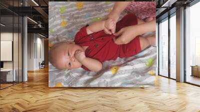 Adorable six month old chubby baby boy having his shirt and pants removed Wall mural