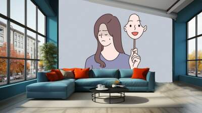 Mood changes, Schizophrenia and mental problems concept. Portrait of young sad woman suffering from multiple personality disorders holding happy mask in hand over grey background vector illustration  Wall mural