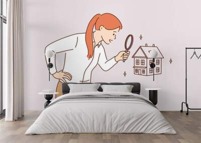 Searching for new house and real estate concept. Young positive business woman standing using magnifying glass zooming to see house or residential building details for making deal  Wall mural