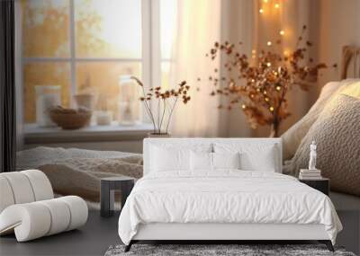 Two burning candles on a tray with dried flowers and a throw blanket on a bed. Wall mural