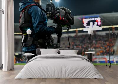 Cameraman behind playing field during soccer match. Wall mural