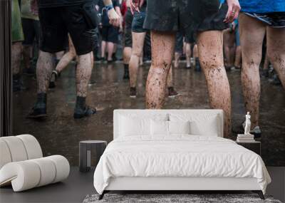 Dirty legs of people dancing in the mud during concert. Wall mural