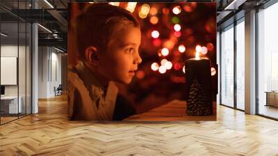 seven year old boy with candle and christams tree in the background Wall mural