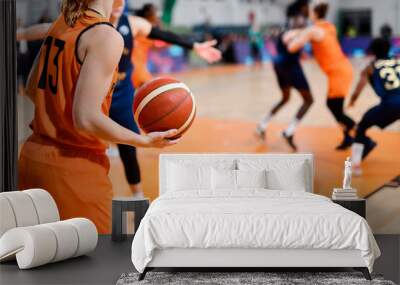 Woman player keeps the ball during basketball match. Wall mural