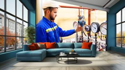 Technician worker on oil and gas refinery checks pressure manometers. Wall mural