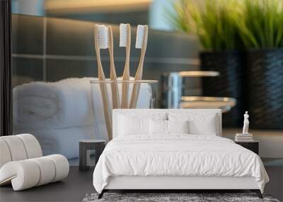 A close-up of toothbrushes in a transparent glass next to white towels on a bathroom table. Wall mural