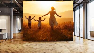 A group of children run across the grass at sunset at a sun silhouette. Childhood dream concept. Children at sunset have fun on the grass. Wall mural