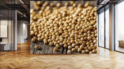 A pile of dried coriander seeds is set on an old wooden surface. Wall mural