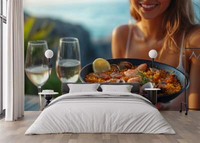 A woman savoring authentic paella by the sea while enjoying a sunny day in a coastal paradise Wall mural