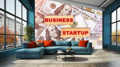 Against the background of dollar bills, the text is written on wooden blocks - business startup Wall mural