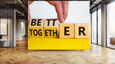 Better together symbol. Businessman turns cubes and changes the word together to better. Beautiful yellow table, white background, copy space. Business, motivational and better together concept. Wall mural