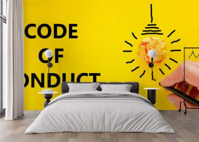 Code of conduct symbol. Businessman writing words 'Code of conduct', isolated on beautiful yellow background. Light bulb icon. Business and code of conduct concept. Copy space. Wall mural