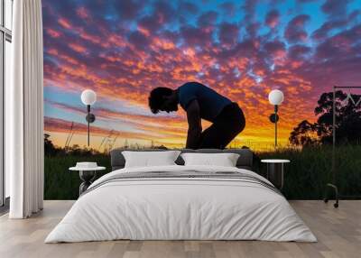 Concept of prayer. Silhouette of a praying young man. Set against a vibrant sunrise sunrise sunset sky. Clasped hands. Also related to sacrifice, spirituality, shepherds, trinity, and shadows. Wall mural