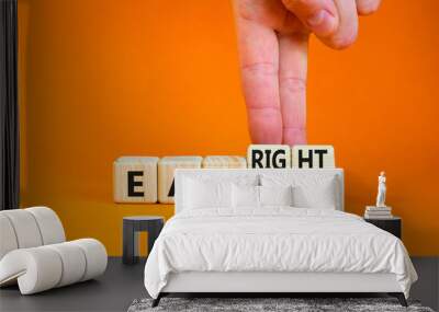 Eat less or right symbol. Concept words Eat less or Eat right on wooden cubes. Beautiful orange table orange background. Doctor hand. Healthy lifestyle and eat less or right concept. Copy space. Wall mural