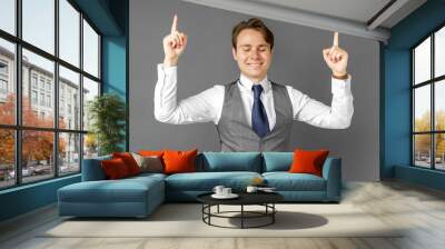 Emotional portrait of a businessman who shows his hands up. Gray background. Wall mural