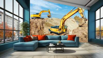 two excavator are digging soil in the construction site on sky background,with white fluffy cloud Wall mural