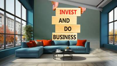 Invest and do business symbol. Concept word Invest and do business on beautiful wooden block. Beautiful grey table grey background. Businessman hand. Invest and do business concept. Copy space. Wall mural