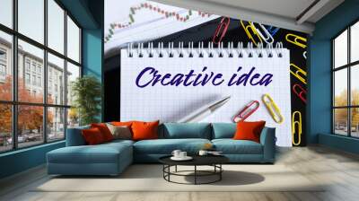 On the desktop are a forex chart, paper clips, a pen and a notebook in which it is written - Creative idea Wall mural