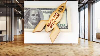 On the dollars lies a wooden model of a rocket with the inscription - GOALS AND OBJECTIVES Wall mural