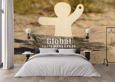 On the sand near the wooden figurine of a man there is a piece of wood with the inscription - Global Warming Wall mural