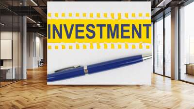 On the table are two sheets from a notebook and a pen on a yellow background written - INVESTMENT Wall mural