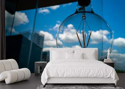 Round glass light bulb on a background of blue sky with clouds. Concept image. Wall mural