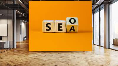 SEO vs SEA. Turned a cube and changed the word 'SEA - search engine advertising' to 'SEO - search engine optimization'. Business and SEO or SEA concept. Beautiful orange background, copy space. Wall mural