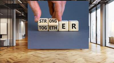 Stronger together symbol. Businessman turns cubes and changes the word together to stronger. Beautiful grey background, copy space. Business, motivational and stronger together concept. Wall mural