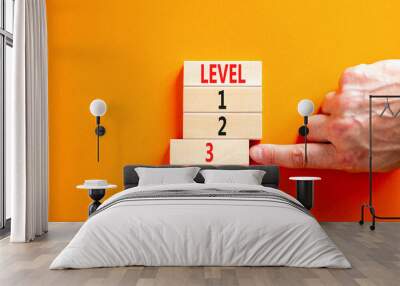 Time to level 3 symbol. Concept word Level 1 2 3 on wooden block. Businessman hand. Beautiful orange table orange background. Business planning and time to level 3 concept. Copy space. Wall mural