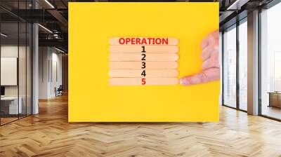 Time to operation 5 symbol. Concept word Operation 1 2 3 4 5 on wooden sticks. Businessman hand. Beautiful yellow table yellow background. Business planning and time to operation 5 concept. Copy space Wall mural