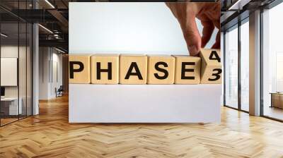 Time to Phase 4. Hand is turning a cube and changes the word 'Phase 3' to 'Phase 4'. Beautiful white background. Business and phase 4 concept. Copy space. Wall mural