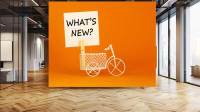 What is new symbol. White sheet of paper. Words 'what is new'. Miniature bicycle model. Beautiful orange background. Business and what is new concept, copy space. Wall mural