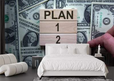 Wooden blocks form the words 'plan 1, 2, 3' on beautiful background from dollar bills. Male hand. Business concept. Copy space. Wall mural