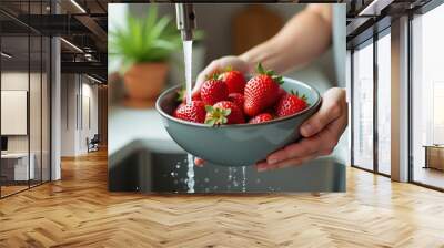 Closeup of the woman holding the gray bowl with strawberries and berries above the kitchen sink, washing the healthy and sweet summer fruits with water from the faucet Wall mural