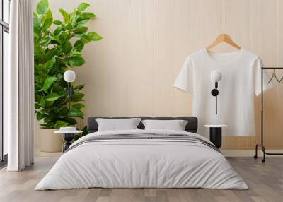 A white shirt is hanging on a wooden hanger. The shirt is placed on a shelf next to a potted plant. Concept of simplicity and minimalism, with the focus on the shirt and the plant. Wall mural