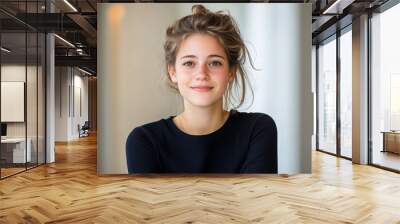 A woman with long brown hair is smiling at the camera. She is wearing a black shirt and has her hair in a bun Wall mural