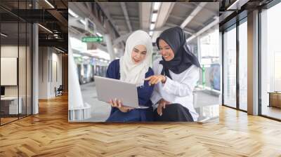 Beautiful young Asian girl two person working at a skytrain with a laptop. Muslim women Wall mural