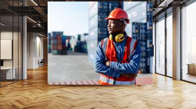 Black male African American smiling engineering in uniform wear hard hat standing containers yard. Area logistics import export and shipping. Wall mural